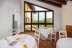 une salle à manger avec deux tables et une grande fenêtre dans l'établissement Al Pompiere - Wine and rooms, à Capriva del Friuli