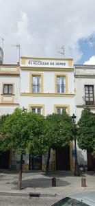 un edificio blanco y amarillo con un letrero. en Apartamentos El Alcazar de Jerez, en Jerez de la Frontera