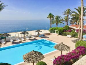 una piscina con sombrillas y el océano en Ocean view apartments Las Flores I, en San Agustín