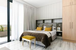 a bedroom with a bed with yellow pillows and a chair at Cambridge Suites -#1 Spectacular Balcony in Cape Town