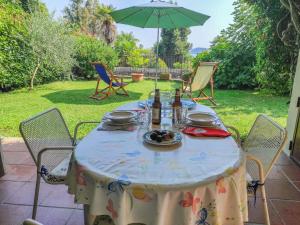 uma mesa com garrafas de vinho com cadeiras e um guarda-sol em Apartment Lo Scoiattolo by Interhome em Belgirate