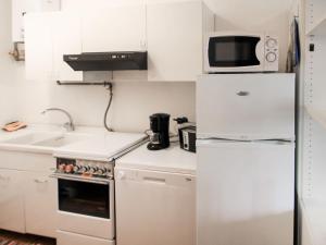 a white kitchen with a refrigerator and a microwave at Apartment Lo Scoiattolo by Interhome in Belgirate +19 photos