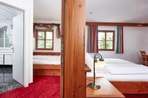 a bedroom with two beds and a red rug at Hotel Hubertus in Brixen im Thale
