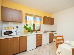 een keuken met houten kasten en een witte magnetron bij Holiday Home Kristina - ROJ427 by Interhome in Žminj
