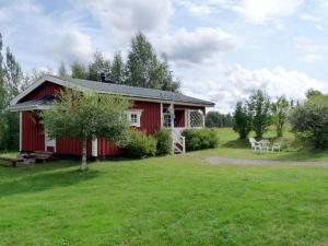 Vemhån的住宿－Chalet Vemhån Östholmen by Interhome，一座红色的房子,在田野里放着两把白色椅子