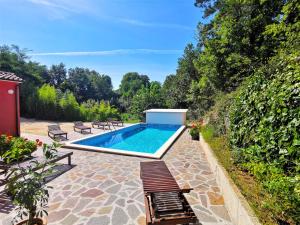 a swimming pool in a garden with chairs and trees at Apartment Vinka - ROJ434 by Interhome in Žminj
