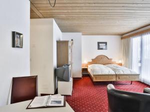 グリンデルワルトにあるApartment Chalet Abendrot-8 by Interhomeのベッド、デスク、椅子が備わるホテルルームです。