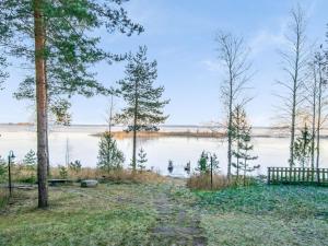un chemin à côté d'un lac avec des arbres et un banc dans l'établissement Holiday Home Wilkkilä by Interhome, à Ruokola