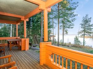 a wooden porch with a table and chairs on a lake at Holiday Home Wilkkilä by Interhome in Ruokola