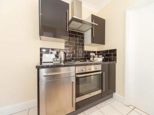 a kitchen with stainless steel appliances and black tiles at BellaLiving 2 Bedroom Apartment - Luton in Luton