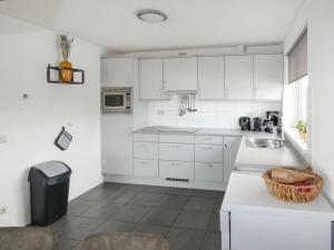 een keuken met witte kasten en een wastafel bij Holiday Home De Meerparel by Interhome in Uitgeest
