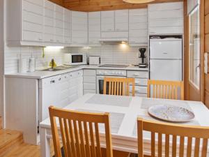 eine Küche mit weißen Schränken und einem Tisch mit Stühlen in der Unterkunft Holiday Home Vuosseli-kelkka 15a by Interhome in Ruka