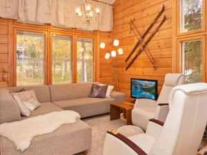 ein Wohnzimmer mit einem Sofa und einem TV in der Unterkunft Holiday Home Vuosseli-kelkka 15a by Interhome in Ruka