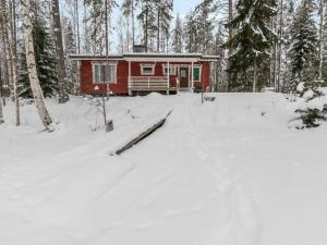 a red cabin in the woods in the snow at Holiday Home Taimisto by Interhome in Juhanala