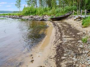 a boat sitting on the shore of a river at Holiday Home Rantakumpu by Interhome in Lieksa