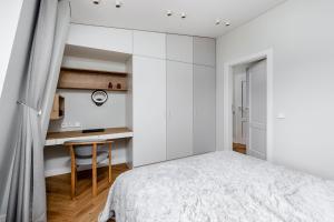 a white bedroom with a bed and a desk at V33 cozy apartment in Druskininkai