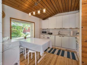 a kitchen with white cabinets and a table with chairs at Holiday Home Lampaluodon punainen tupa by Interhome in Tyltty