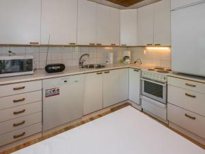 a kitchen with white cabinets and a sink and a microwave at Holiday Home Lampaluodon punainen tupa by Interhome in Tyltty