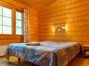 ein Schlafzimmer mit einem Bett in einer Blockhütte in der Unterkunft Holiday Home Otso by Interhome in Lahdenperä