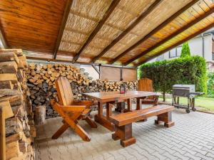 eine Terrasse mit einem Holztisch, Bänken und einem Grill in der Unterkunft Holiday Home Penzion Jindřiška by Interhome in Tatobity