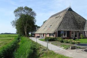 a building with a thatched roof and a table at De Bedstee in Holwerd