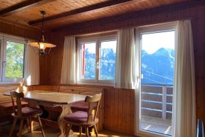 - une salle à manger avec une table, des chaises et des fenêtres dans l'établissement Schwendihöckli - CharmingStay, à Flumserberg