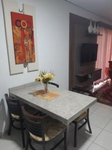 uma mesa de jantar com um vaso de flores em Apartamento Enseada Nautico Residence em Caldas Novas