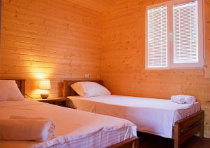 two beds in a room with wooden walls and a window at Finca Idoize Camping Hotel in Akhmety