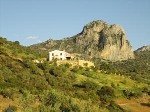 une maison sur une colline avec une montagne en arrière-plan dans l'établissement Rancho Los Cuñaos, à El Gastor