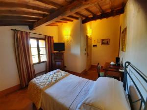 a bedroom with a bed and a desk and a window at Villa Curina Resort in Castelnuovo Berardenga