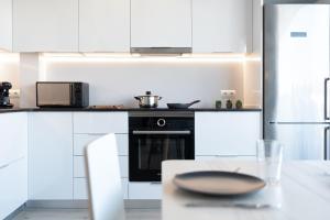 a kitchen with white cabinets and a black oven at Hauzify I Apartament 4Winds in Sant Feliu de Guixols