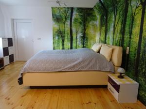 a bedroom with a bed with a forest wall mural at Kommod Stuv in Langstedt