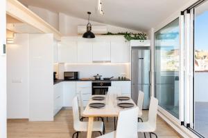 a kitchen with white cabinets and a wooden table and chairs at Hauzify I Apartament 4Winds in Sant Feliu de Guixols