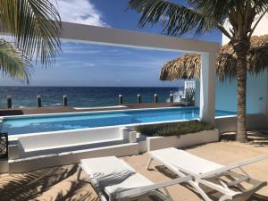 a swimming pool with two chairs and the ocean at Beach House Pietermaai in Historic Pietermaai District in Willemstad