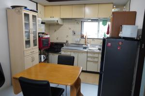 una pequeña cocina con mesa y nevera en MINPAKU-P 民泊p, en Izumisano