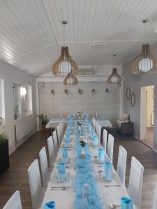 una mesa larga con sillas blancas y servilletas azules en Reštaurácia-penzión ALTANA, en Ludanice