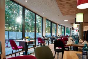 ein Restaurant mit Tischen und Stühlen und großen Fenstern in der Unterkunft Soloplan City Resort in Kempten