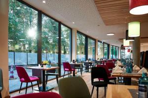 a restaurant with tables and chairs and large windows at Soloplan City Resort in Kempten