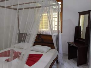 a bedroom with a bed with a mosquito net at Blooming Villa & Guest in Matara