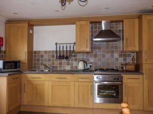 uma cozinha com armários de madeira e um forno com placa de fogão em Low Dow Crag em Coniston