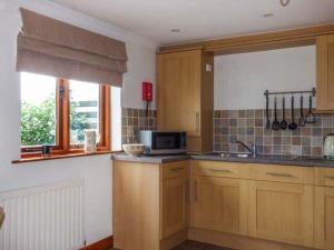 a kitchen with wooden cabinets and a microwave at Low Dow Crag in Coniston