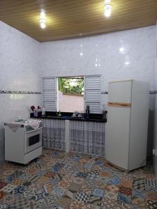 uma cozinha com um frigorífico branco e uma janela em CHALÉ POUSADA DO SONHO Guapimirim-RJ em Guapimirim