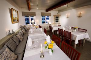 a restaurant with tables and couches with flowers on them at Landhaus Altes Pastorat in Süderende