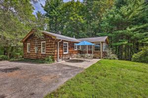 a log cabin with a blue umbrella in a yard at Peaceful Roaring Gap Retreat with Fire Pit and Patio! in Roaring Gap
