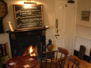 a dining room with a fireplace and a table and chairs at The Red Lion Hinxton in Hinxton