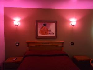 a bedroom with a bed and two lights on the wall at Deluxe Motel, Los Angeles Area in Downey
