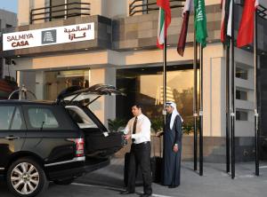 deux hommes debout à côté d'une voiture avec son coffre ouvert dans l'établissement Salmiya Casa Hotel, à Koweït