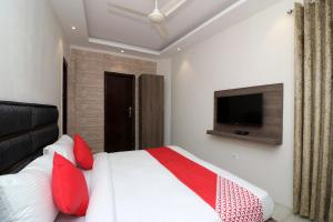 Schlafzimmer mit einem Bett mit roten Kissen und einem TV in der Unterkunft OYO Flagship Hotel Madhurapuri in Kozhikode
