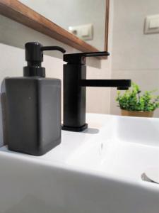 a black soap dispenser sitting on top of a sink at Acogedor apartamento en EL VALLE DEL JERTE 1 in Piornal