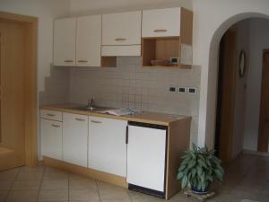 una cocina con armarios blancos y fregadero en Ferienwohnung im Haus Texel IV, en Rablà